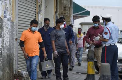 A Bahraini police officer instructs foreign workers to wear protective gear amid the Covid-19 pandemic, in the old marketplace of the capital Manama. AFP