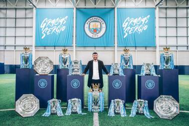Sergio Aguero poses alongside the 15 trophies he has won at Manchester City. Courtesy photo