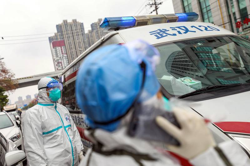 A fully protected ambulance staff waits for his colleague to take an order outside the hospital in Wuhan, Hubei province, Chin.  EPA