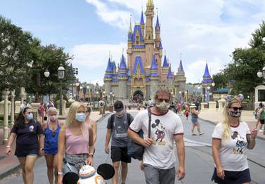 Guests wear masks at the official reopening day of the Magic Kingdom at Walt Disney World in Florida last month. A $1bn resort technology project is one of the the investments that has been cut as Walt Disney focuses on its Disney+ streaming platform. AP Photo 