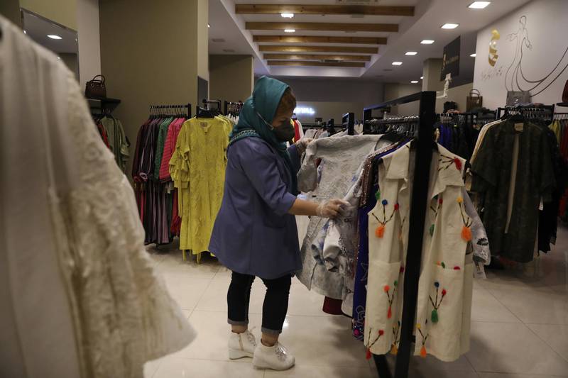 A woman wearing a face mask inspects clothes at a store in Bamland shopping mall, in Western Tehran, March 15. AP Photo