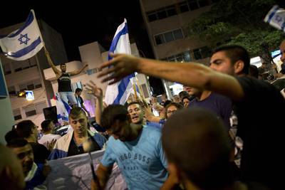 An Israeli right wing activist waves the Israeli flag in support of Israel's offensive in Gaza, during a demonstration, in Tel Aviv, Israel on July 19, 2014. Oded Balilty/AP Photo