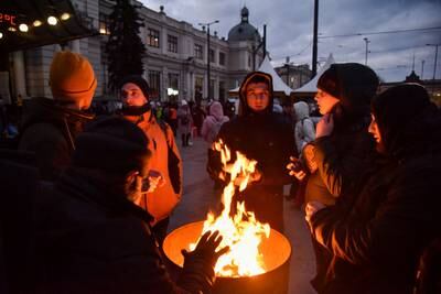 People fleeing Russia's invasion of Ukraine warm up by a fire near the train station in Lviv, Ukraine. Reuters