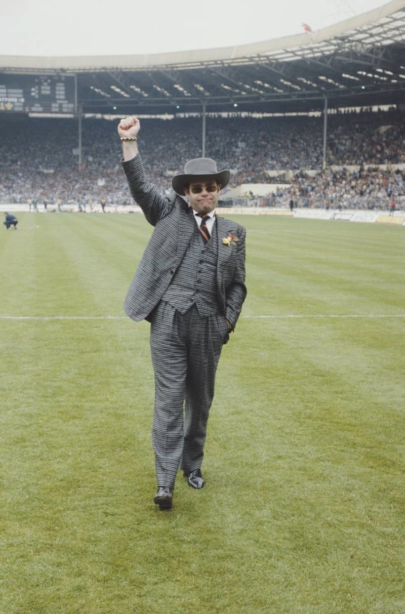 Elton John, wearing a grey pin-striped suit, attends the FA Cup Final in Wembley Stadium, London on May 19, 1984. Getty Images