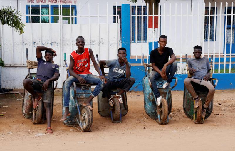 Men sit on wheelbarrows in Bissau, the capital of Guinea-Bissau, as part of an official visit of Emmanuel Macron, the French President. AFP