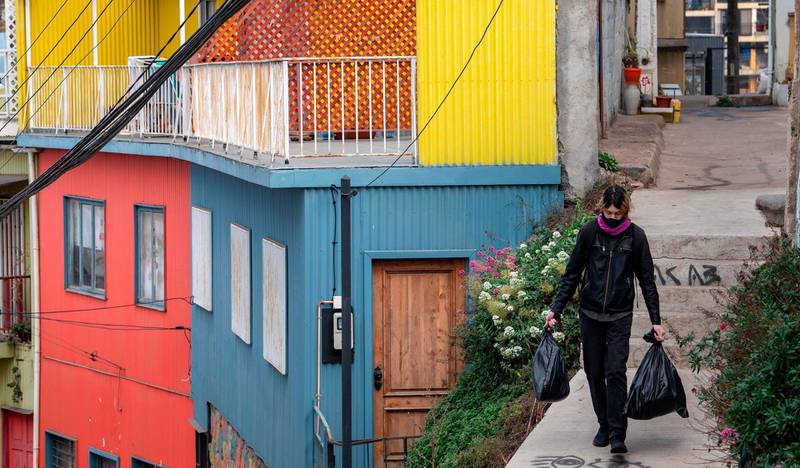 A woman carries bags as she walks down a hill in Valparaiso. Elevators in the city are currently out of operation due to the coronavirus pandemic. AFP