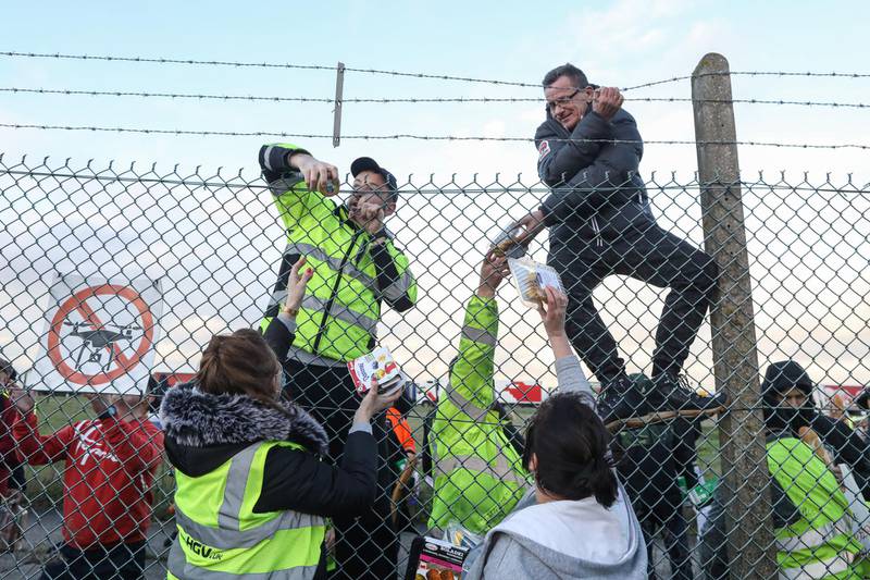 Volunteers distribute fresh food and supplies over a perimeter fence to truck drivers at Manston airport in Manston, U.K. Routes to Dover, Britain's busiest cross-channel port, have been choked for days after France shut its border with Britain, blaming an outbreak of a novel strain of the coronavirus. Bloomberg