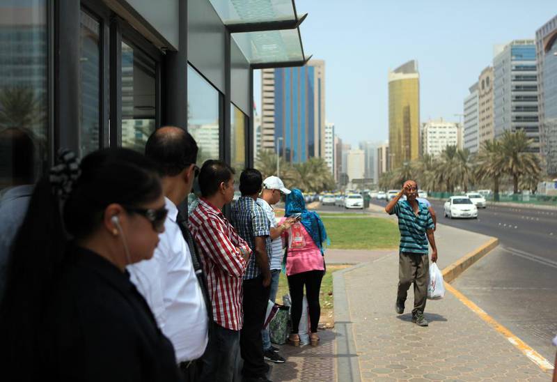 People stand outside a bus shelter in Abu Dhabi because the AC does not work. Ravindranath K / The National