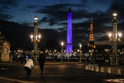 epaselect epa08867509 A man takes a picture of another as Eiffel Tower and Luxor Obelisk with blue lights as the Christmas illuminations were switched on in The Place de la Concorde in Paris, France, 06 December 2020  EPA/MOHAMMED BADRA