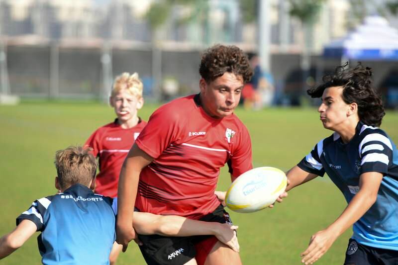 Young rugby players in action for the under 12 boys with DESC player holding the ball vs BSAK during the BSAK 7s tournament held at Zayed Cricket Stadium, Abu Dhabi. Khushnum Bhandari / The National