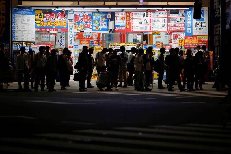 People stand in front of an electronics store in Tokyo. Japan's sluggish economy has prompted the prime minister Shinzo Abe to delay a sales tax hike by more than two years. Toru Hanai/Reuters