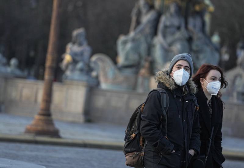 People wearing face masks to protect against Covid-19 cross the Concorde square in Paris.  The World Health Organisation says early evidence suggests the omicron variant may be spreading faster than the highly transmissible delta variant, but brings with it less severe coronavirus disease. AP