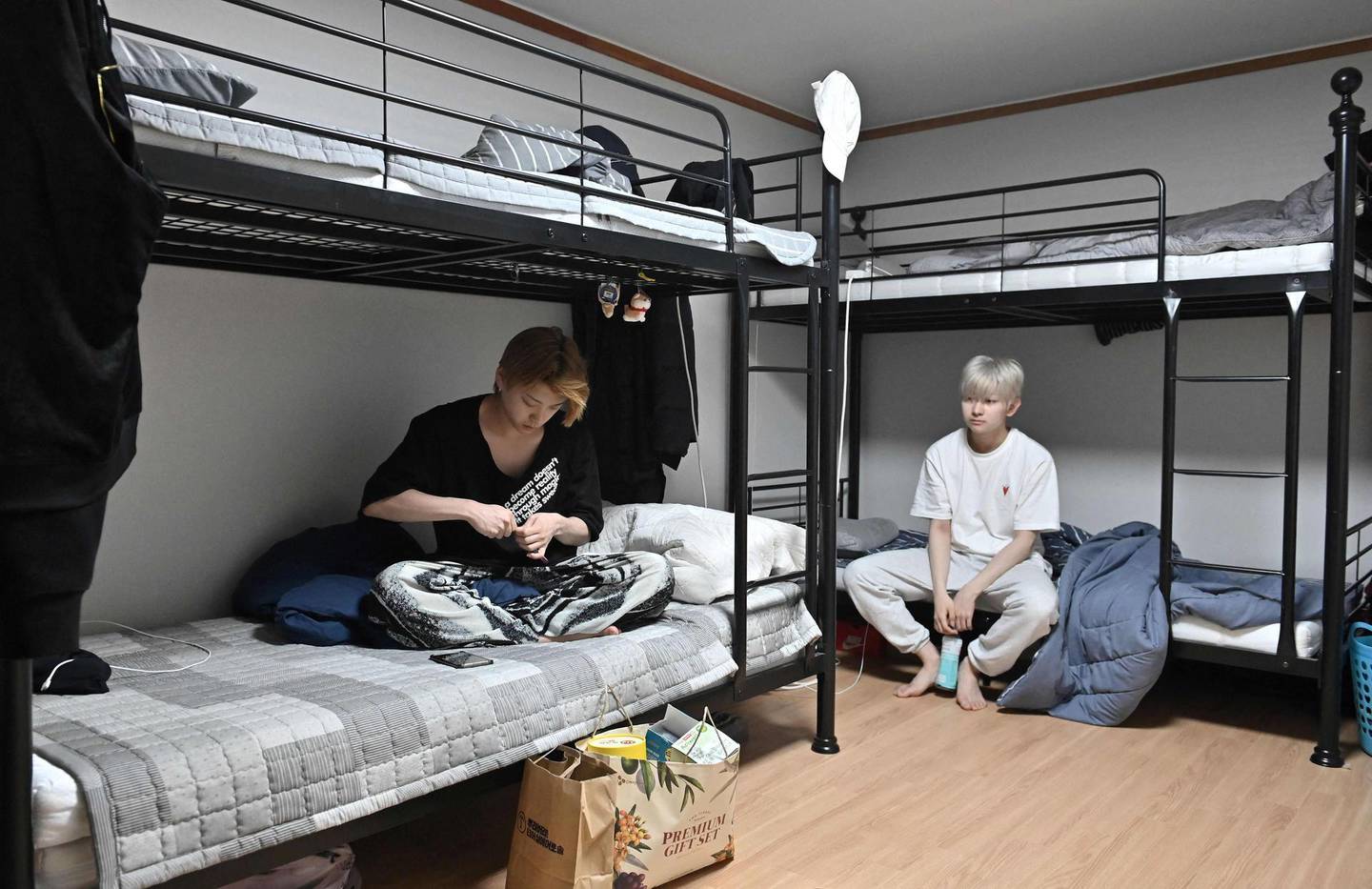 This picture taken on April 29, 2021 shows K-pop boy band Blitzers members Jang Jun-ho (L) and Lee Jun-young (R) sitting on bunk-beds after waking up in the band's shared house in Seoul. Thirty teenagers, thousands of hours of training, dozens of shattered dreams: it all comes to a head next week when the Blitzers will be launched into the cut-throat K-pop market, hoping to become the next BTS. - TO GO WITH SKorea-music-social-entertainment-Kpop,FOCUS by Kang Jin-kyu
 / AFP / Jung Yeon-je / TO GO WITH SKorea-music-social-entertainment-Kpop,FOCUS by Kang Jin-kyu
