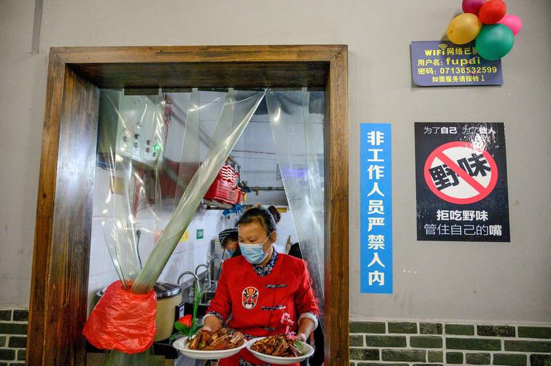 A waitress carries meals out of the kitchen at a restaurant in Macheng in China’s central Hubei province on March 25, 2020. AFP