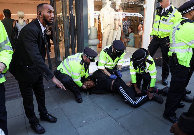 Police officers detain a person as disruptors target shops during a shoplifting spree flash mob on Oxford Street in London. Reuters