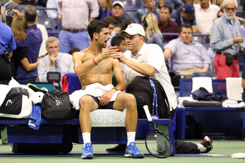Novak Djokovic of Serbia is looked over by a trainer during a break in play. AFP