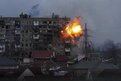 An explosion tears a hole in the side of an apartment building after a Russian tank fired a rocket in Mariupol on March 11. AP Photo