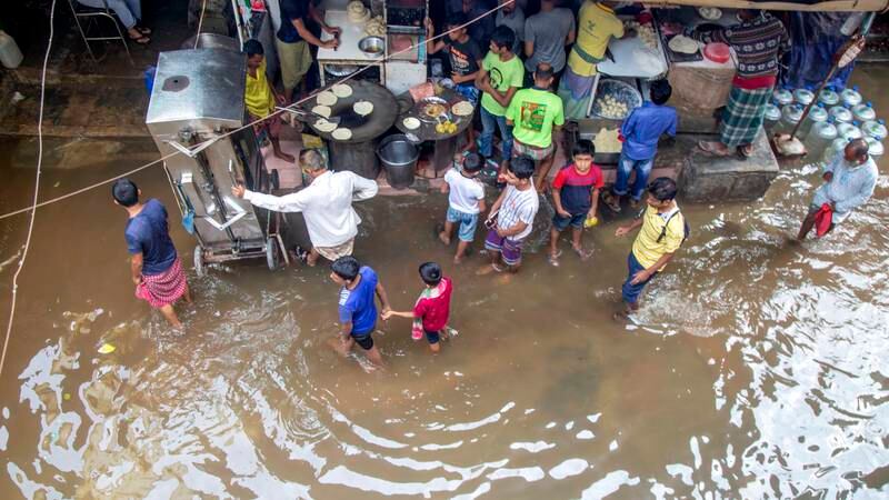 Bangladeshis walk through a flooded area after the passing of the cyclone in Dhaka. EPA