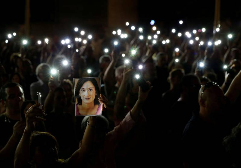 People hold up photos of assassinated anti-corruption journalist Daphne Caruana Galizia and torches on mobile phones during a vigil to mark eleven months since her murder in a car bomb, in Valletta, Malta. Darrin Zammit Lupi/Reuters