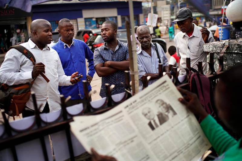 Congolese men talk at a news stand in Kinshasa, Congo, Tuesday Jan. 8, 2019. As Congo anxiously awaits the outcome of the presidential election, many in the capital say they are convinced that the opposition won and that the delay in announcing results is allowing manipulation in favor of the ruling party. (AP Photo/Jerome Delay)