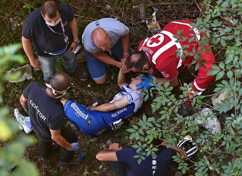 (FILES) In this file photo taken on August 15, 2020 Deceuninck - Quick Step Belgium rider Remco Evenepoel is helped by staff member and medical staff as he lies down after crashed during the 114th edition of the giro di Lombardia (Tour of Lombardy),  a 231 km cycling race from Bergamo to Como. A few days before the start of the Tour de France, after the fall of Remco Evenepoel during the Tour of Lombardy and the one of Fabio Jakobsen during the Tour of Poland, the the cyclist struggle with this series of accidents which marked the resumption of the races. / AFP / Marco BERTORELLO
