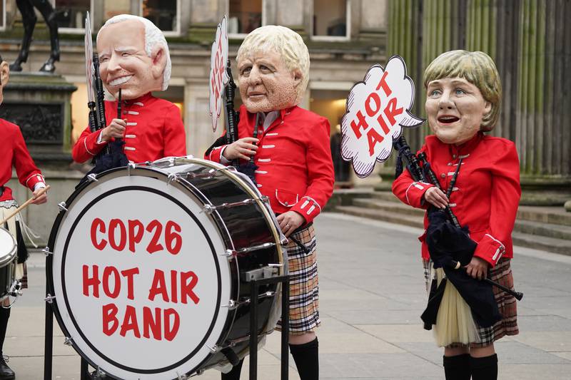Environmental campaigners with 'big heads' of world leaders, including Joe Biden and Boris Johnson, dress in kilts and carry bagpipes as they gather in Royal Exchange Square, central Glasgow. PA
