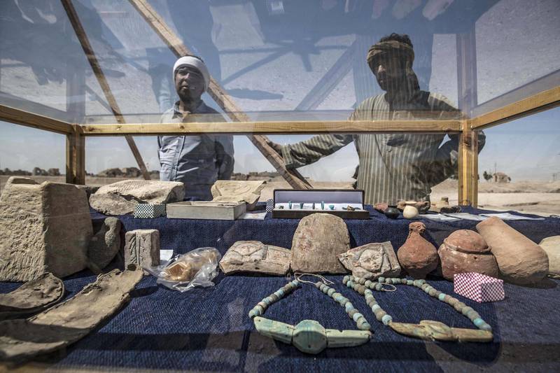 Workers stand next to a display of jewellery and other artefacts uncovered  at the site of a 3,000-year-old city uncovered by an Egyptian archaeological mission near Luxor. AFP