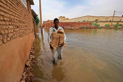 A Sudanese man holds bags to build a barricade to walk in flood waters in Tuti island, where the Blue and White Nile merge in the Sudanese capital Khartoum. AFP