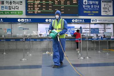 A worker wearing protective gear sprays disinfectant as part of preventative measures against the spread of covid-19 at a railway station in Daegu, South Korea.  AFP
