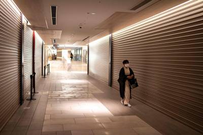 A woman walks past closed shops in a department store in Tokyo during a coronavirus state of emergency covering Tokyo, Osaka, Kyoto and Hyogo regions. AFP