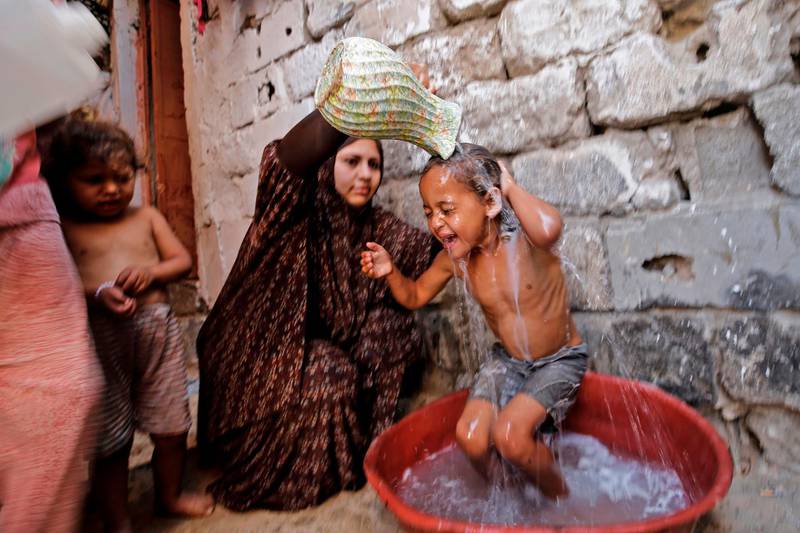 A Palestinian mother gives her children a bath amid a heatwave during the ongoing pandemic crisis in Gaza City.  AFP