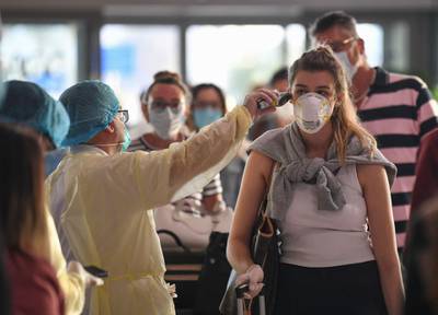 A health worker checks the body temperature of passengers bound for Frankfurt at Dubai International Airport.