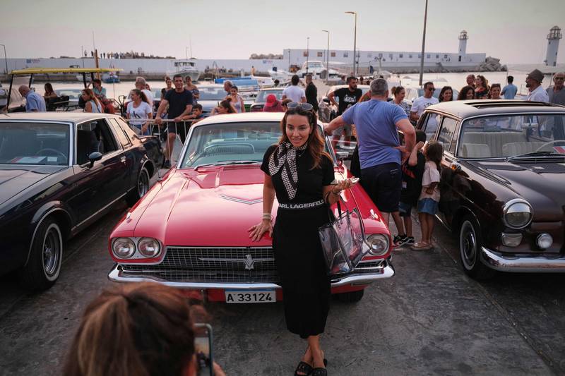 A woman poses for a picture in front of a 1966 Ford Thunderbird.