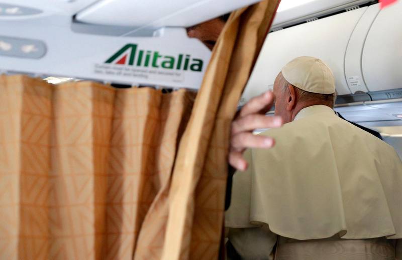 Pope Francis returns to his seat after meeting with reporters aboard his plane. AFP