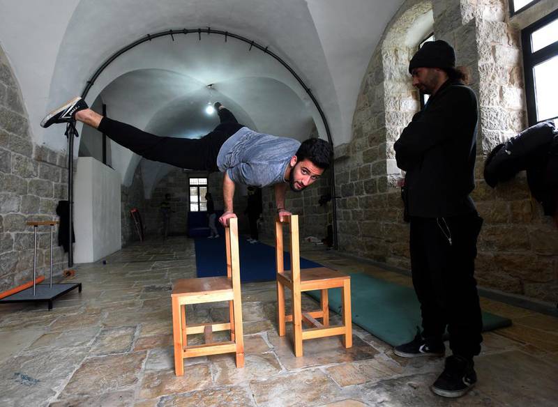 A Palestinian performer balances himself on two chairs. Other activities include juggling balls, clubs, diabolo and scarfs; balancing on the Chinese pole or a tight wire; and pedalling on a unicycle.