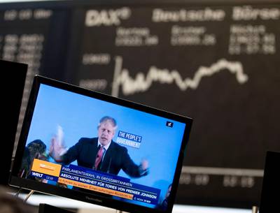 Britain's Prime Minister Boris Johnson is seen on a television screen at the stock market in Frankfurt, Germany, Friday, Dec. 13, 2019. In the background is the German stock market indicator, DAX. (AP Photo/Michael Probst)