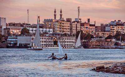 TOPSHOT - Egyptian children sit on a surfboard with an improvised sail in the Nile river in the southern city of Aswan, some 920 kilometres away from the capital Cairo on November 24, 2017. / AFP PHOTO / KHALED DESOUKI