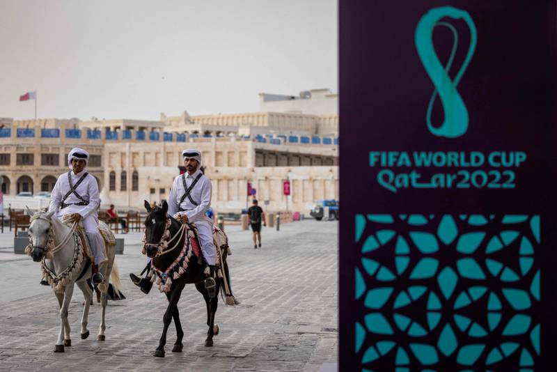Horse-mounted guards patrol past a FIFA sign in a market area in Doha. AFP
