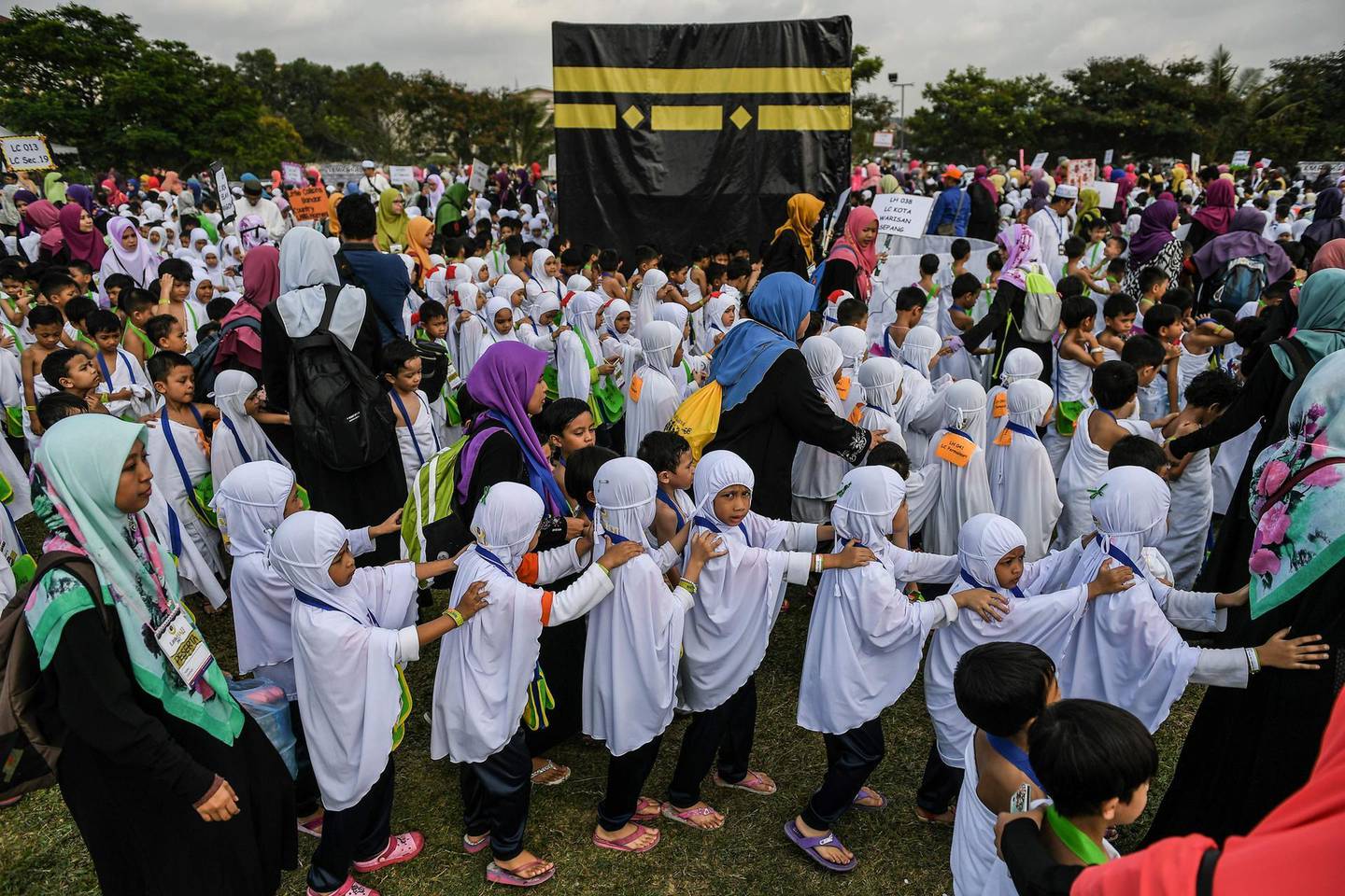 Malaysian children from the Little Caliphs kindergarten circumambulate a mockup of the Kaaba, Islam's most sacred structure located in the holy city of Mecca, during an educational simulation of the Hajj pilgrimage in Shah Alam, outside Kuala Lumpur on July 24, 2017.    
Thousands of Malaysian children took part in a practice run for the Muslim hajj pilgrimage on July 24, walking round a model of the holy Kaaba shrine under the tropical sun. The hajj is one of the five pillars of Islam, which capable Muslims must perform at least once, and marks the spiritual peak of their lives. / AFP PHOTO / MOHD RASFAN