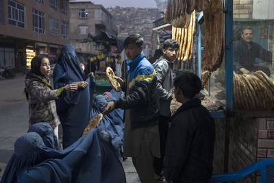 A man distributes bread to Afghan women outside a bakery in Kabul on Thursday. AP