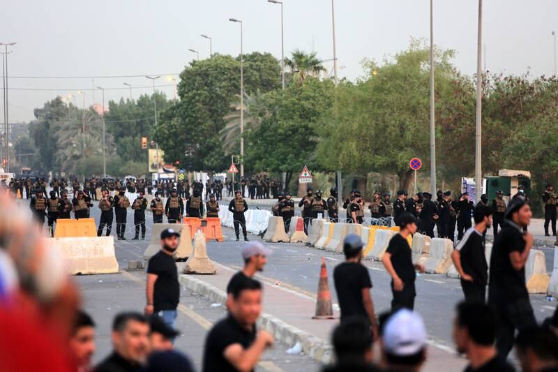 Iraqi security forces stand guard as Mr Al Sadr's supporters gather in front of the parliament building in Baghdad. EPA