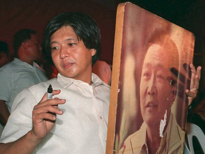 Ferdinand Marcos Jr, also known as 'Bongbong', autographs a portrait of his father during a campaign rally in Manila on May 5, 1995. AFP