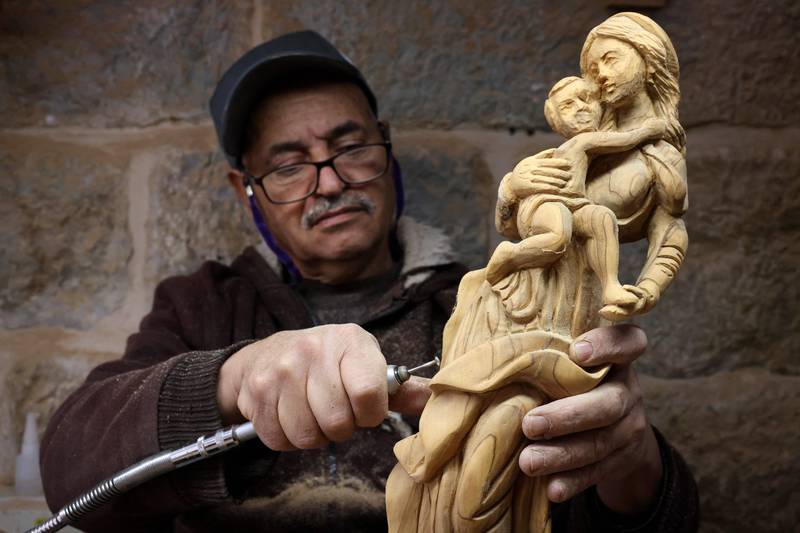 A Palestinian craftsman prepares Advent-themed souvenir figurines ahead of Christmas at a workshop in the biblical city of Bethlehem in the occupied West Bank on December 13, 2022.  (Photo by HAZEM BADER  /  AFP)