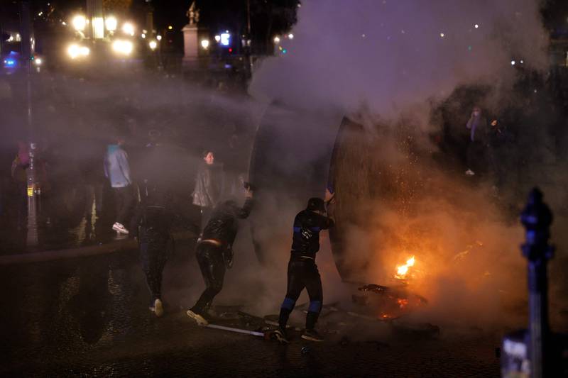 Police use water cannon as protesters roll a wooden cable reel drum. AFP