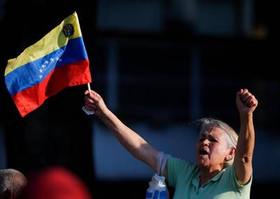 A supporter of opposition leader and self-proclaimed interim president Juan Guaido, holding a Venezuelan flag, cheer him on during a rally in a west side neighborhood in Caracas, Venezuela, Friday, April 5, 2019. At the start of his speech, Guaido acknowledged Venezuela is going through "a very difficult transition", asking for further support to help him topple President Nicolas Maduro. The poster reads in Spanish " Guiado is Venezuela"(AP Photo/Fernando Llano)