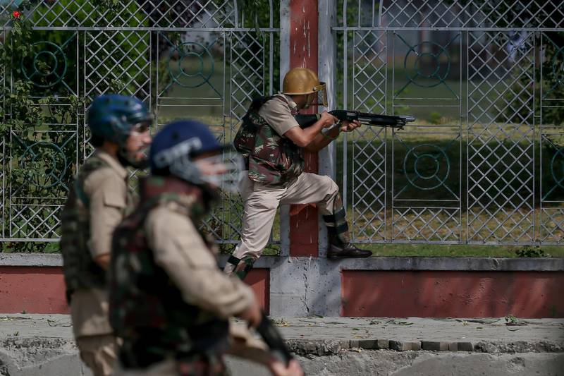 An Indian policeman fires a pellet gun at Kashmiri protesters after Eid prayers in Srinagar, Indian controlled Kashmir, Saturday, June 16, 2018. Police and residents say at least one young man has been killed and over a dozen others wounded as protests against Indian rule followed by clashes erupted in Indian-controlled Kashmir shortly after Eid prayers. (AP Photo/Dar Yasin)