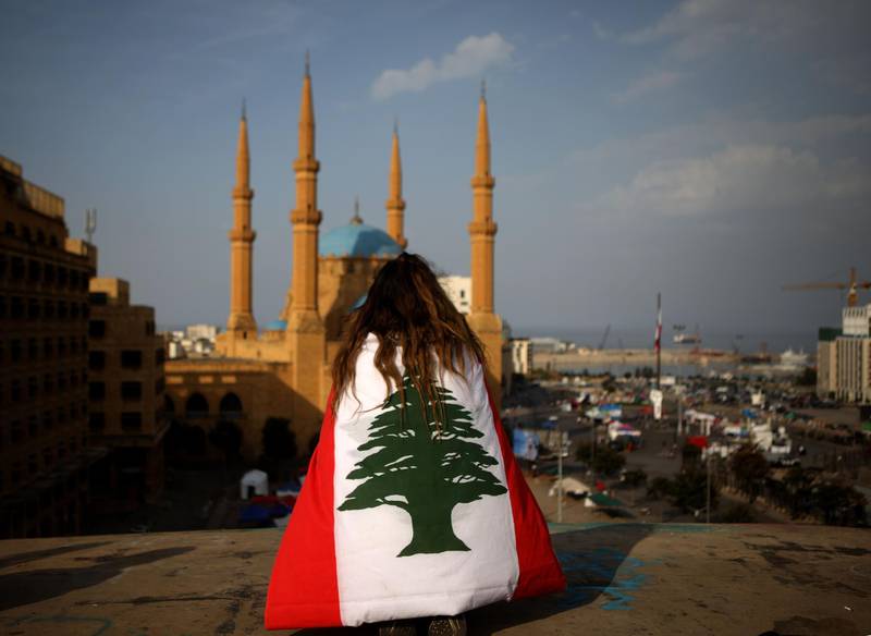 A protester draped in the Lebanese flag sits on the rooftop of the 'Egg' building overlooking the Mohammed Al Amin mosque and the Martyrs square in Beirut on November 14, 2019. AFP