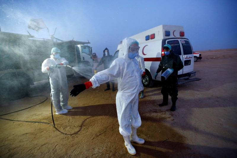 Abdelhussan Kadhim from the PMF, who volunteered to work at the cemetery, wears a protective suit as he is disinfected after the burial of a man who passed away due to coronavirus. REUTERS
