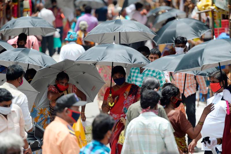 People hold umbrellas distributed by volunteers to maintain social distancing in a market in Chennai. AFP