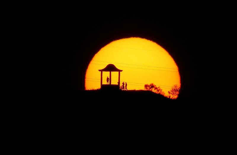 People are silhouetted against the setting sun at "El Mirador de la Alemana" as the summer's second heatwave hits Spain, in Malaga.  Reuters